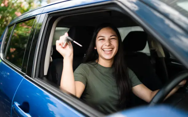 Woman with keys in hand proud of getting the licence to drive on public roads in Auckland, New Zealand.