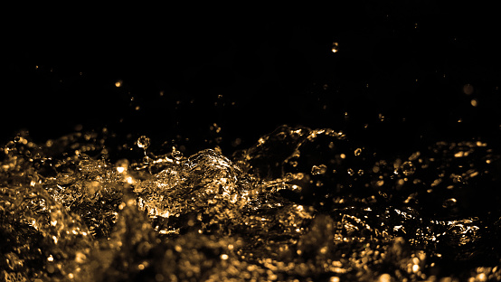 Hi speed close up images of oil liquid from diesel gasoline splashing and moving up to the air on black background. Power of fuel liquid that active and powerful. studio shot premium gold color tone.