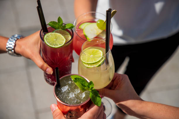 mani che tengono insieme i cocktail in un brindisi - fruit liqueur foto e immagini stock