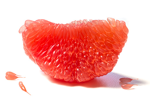 Fresh juicy piece of grapefruit pulp isolated on white background. Piece of peeled grapefruit close up. Slice of citrus fruit wallpaper