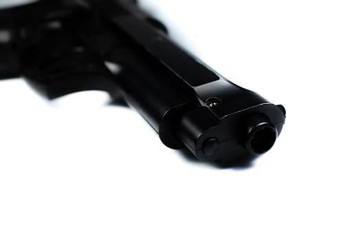 Cañón de un arma negra, pistola yace sobre un fondo blanco. De cerca. photo