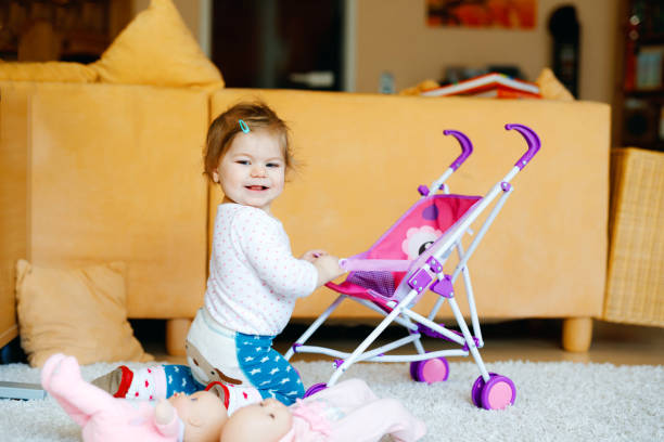 Cute adorable baby girl crawl and play with doll carriage. Beautiful toddler child with pushing stroller with toy at home. Happy kid with two dolls Cute adorable baby girl crawl and play with doll carriage. Beautiful toddler child with pushing stroller with toy at home. Happy kid with two dolls. buggy eyes stock pictures, royalty-free photos & images