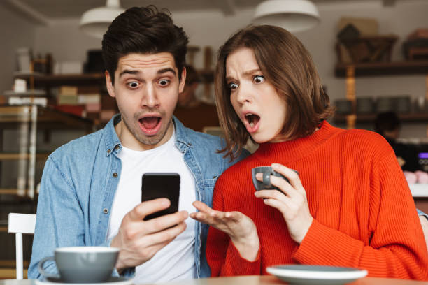 istock Shocked young couple sitting at the cafe table 1303645099