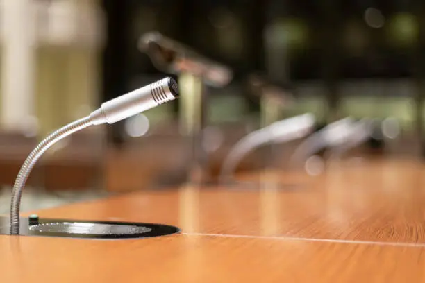 Selective focus and extreme close-up of a microphone with other microphones blurred in the background: concept of communication, media, speech, press, company / lots of copy space