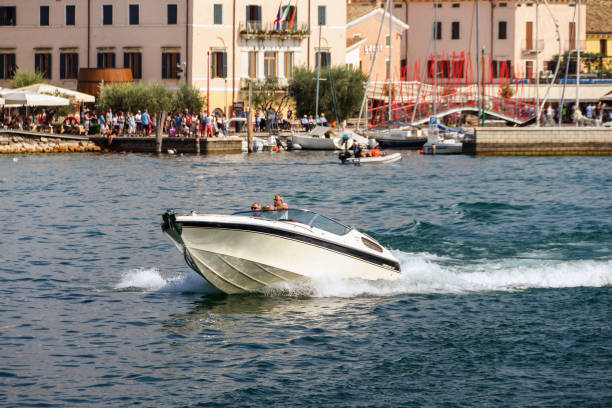 Bardolino, Lake Garda, Italy - September 2018: Private motor boat at speed with the lakefront of Bardolino in the background.