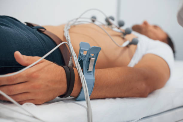 Man lying on the bed in the clinic and getting electrocardiogram test stock photo