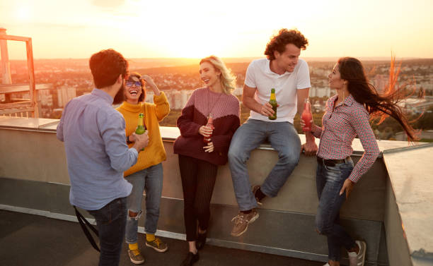 istock Cheerful young friends with drinks having party on rooftop 1303647786