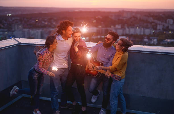 Young friends with sparklers enjoying party on rooftop