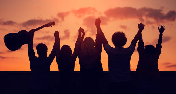 istock Unrecognizable friends with raised arms during sunset 1303647801