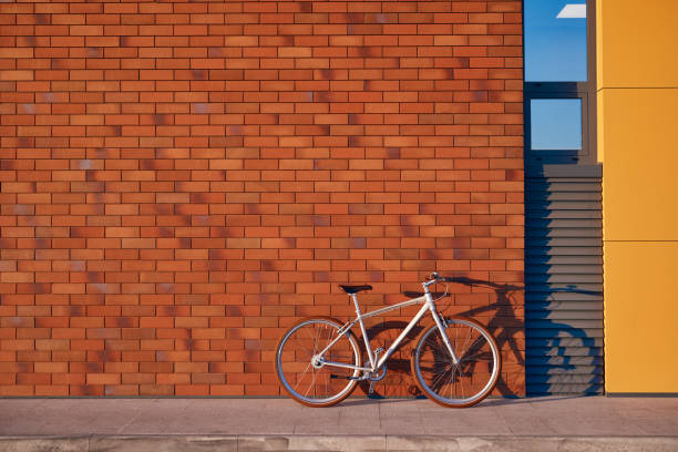 Bike parked on pavement near modern building with brick wall on city street
