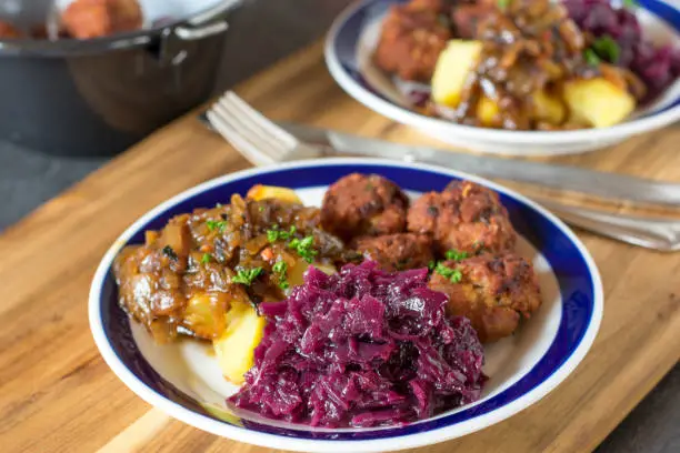 fresh cooked traditional red cabbage vegetables served as a side dish on a dinner plate with meat, potatoes and sauce