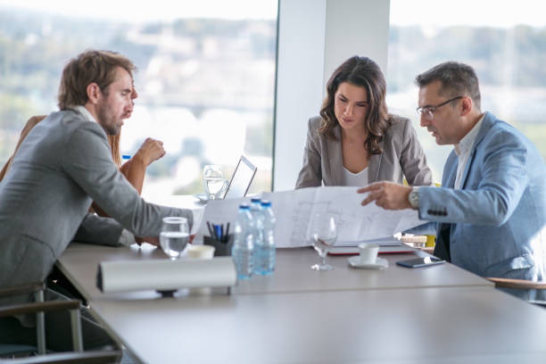 istock Four business people in a meeting at conference table, analyzing plan on spreadsheet 1303648021