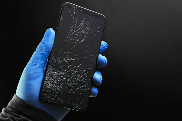 istock A broken touch phone with a cracked screen in your hand on a black background. 1303648951