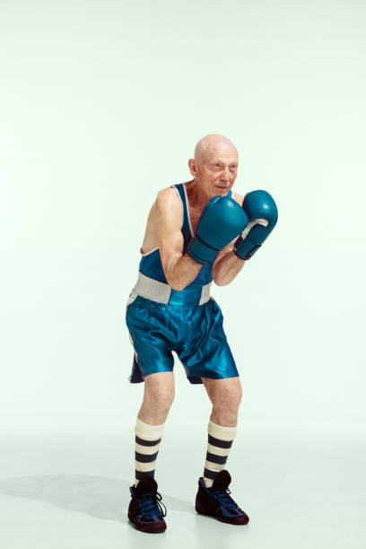 Senior man wearing sportwear boxing isolated on studio background. Concept of sport, activity, movement, wellbeing. Copyspace, ad. Champion. Senior man wearing sportwear boxing on studio background. Caucasian male model in great shape stays active and sportive. Concept of sport, activity, movement, wellbeing. Copyspace, ad. old man boxing stock pictures, royalty-free photos & images
