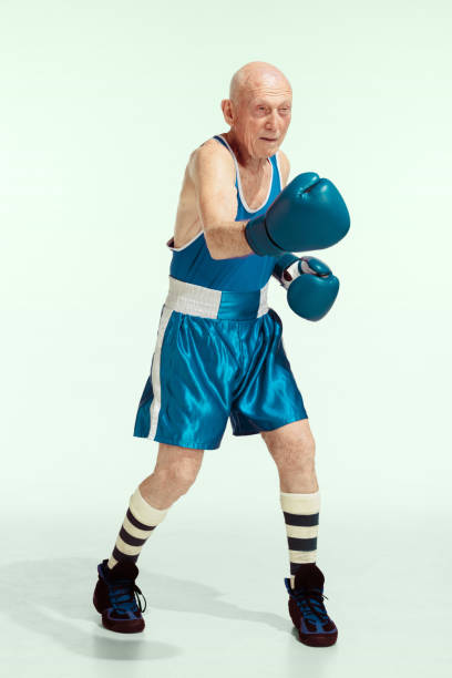 Senior man wearing sportwear boxing isolated on studio background. Concept of sport, activity, movement, wellbeing. Copyspace, ad. Punch. Senior man wearing sportwear boxing on studio background. Caucasian male model in great shape stays active and sportive. Concept of sport, activity, movement, wellbeing. Copyspace, ad. old man boxing stock pictures, royalty-free photos & images