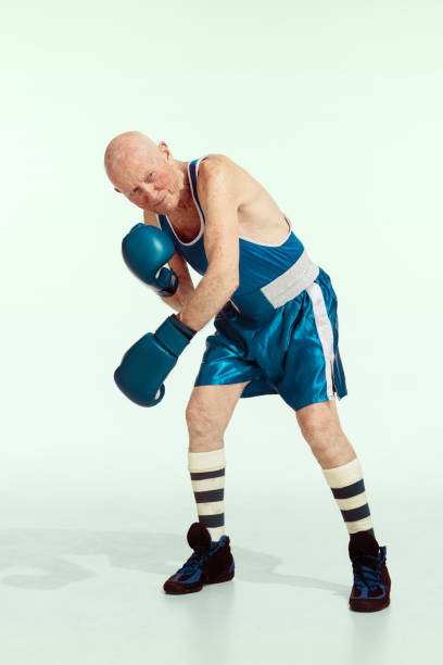 Senior man wearing sportwear boxing isolated on studio background. Concept of sport, activity, movement, wellbeing. Copyspace, ad. Coach. Senior man wearing sportwear boxing on studio background. Caucasian male model in great shape stays active and sportive. Concept of sport, activity, movement, wellbeing. Copyspace, ad. old man boxing stock pictures, royalty-free photos & images