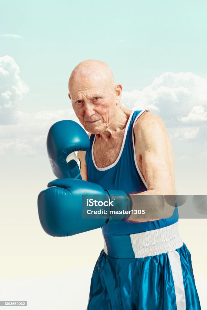 Senior man wearing sportwear boxing on sky background. Concept of sport, activity, movement, wellbeing. Copyspace, ad. Senior man wearing sportwear boxing isolated on sky background. Caucasian male model in great shape stays active and sportive. Concept of sport, activity, movement, wellbeing. Copyspace, ad. Senior Adult Stock Photo