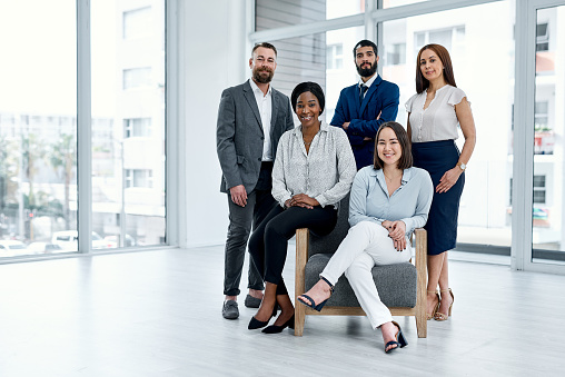 Shot of a group of well-dressed businesspeople standing together. Successful business team smiling teamwork corporate office colleague. Ready to make success happen