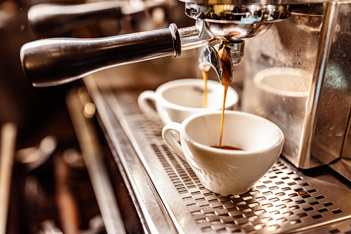 Photo of espresso machine pouring coffee into cups