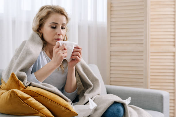 istock Ill woman covered with blanket sit on couch 1303652936
