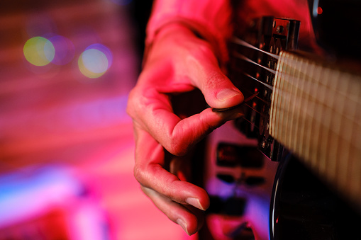 Detail of a woman's hand playing an electric guitar.