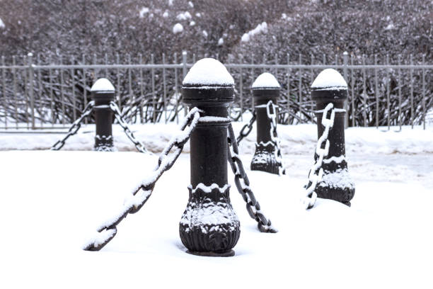 istock Cast iron fence posts with chains, covered with snow 1303654141