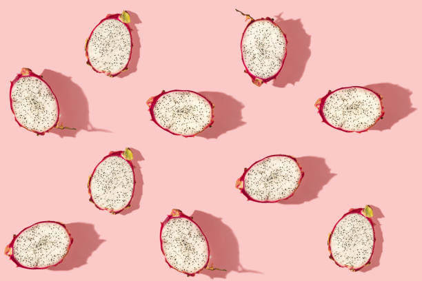 istock Pattern created from fresh exotic dragon fruits halves on pastel pink background. Top view. 1303654623
