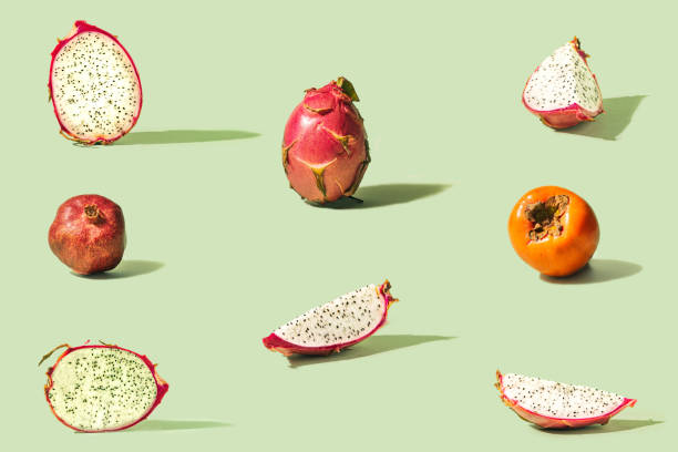 istock Pattern created from fresh exotic fruit khaki, dragon fruit and pomegranate on pastel green background. 1303654657