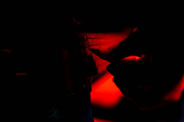 istock A pick strums the strings of a guitar in red backlighting 1303655616