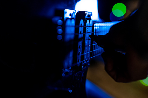 Man's hand on the fretboard of an electric guitar. Selective focus