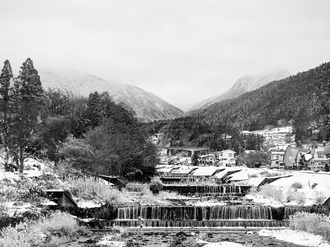 Black and white photo looking up the Kakuma River in winter snow where it meets the Yomase River in Yamanouchi, Nagano Prefecture, Japan.