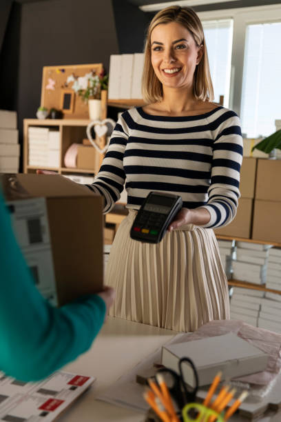 istock Businesswoman holding a credit card reader for a customer while giving the package 1303660226