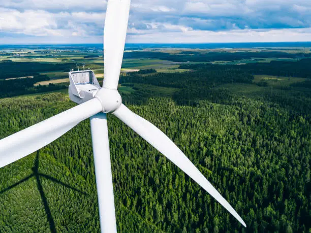 Photo of Aerial view of windmills in green summer forest in Finland close up.