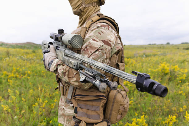 istock Soldier with rifle standing in green field 1303666540