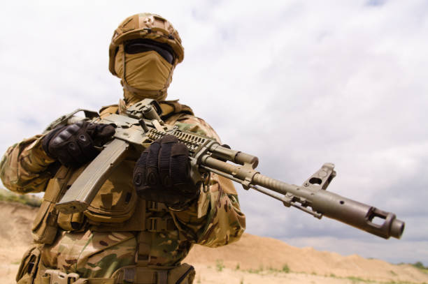 istock Army soldier holding rifle against sky background 1303666627