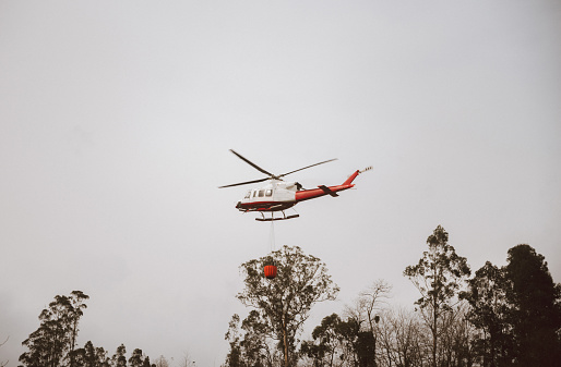 A firefighter helicopter flying to a forest fire