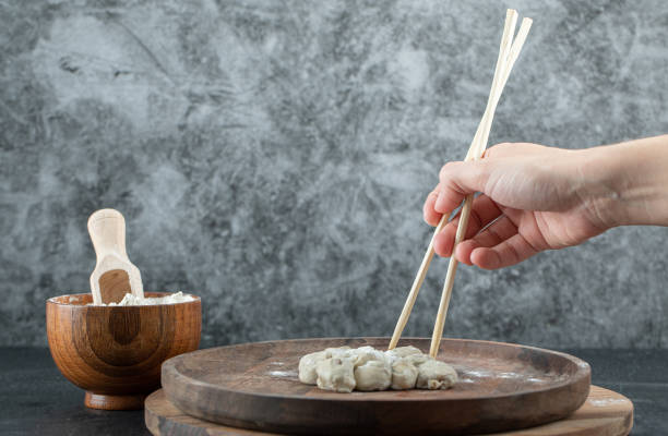 istock Female hand taking dumpling with chopsticks from plate 1303669793