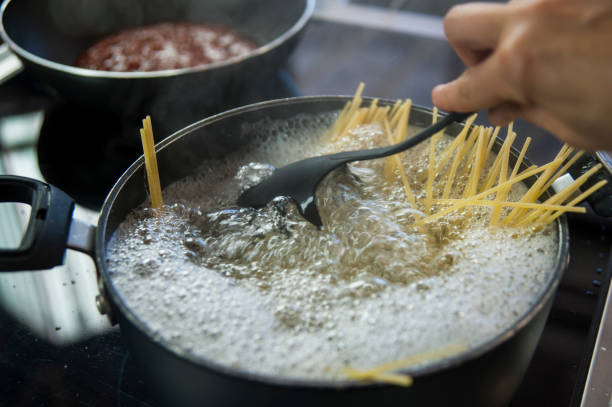 cottura degli spaghetti in una pentola con acqua bollente - mestolo foto e immagini stock