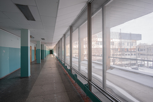 Long bright empty corridor with wide windows of the old building in the style of Soviet modernism, in the afternoon.