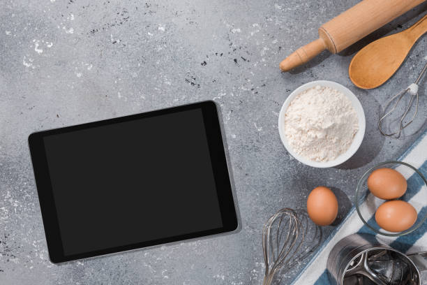 istock Ingredients, tools for baking and tablet with blank screen and place for text or image on gray table. recipe, cookbook, cooking courses online template 1303676097