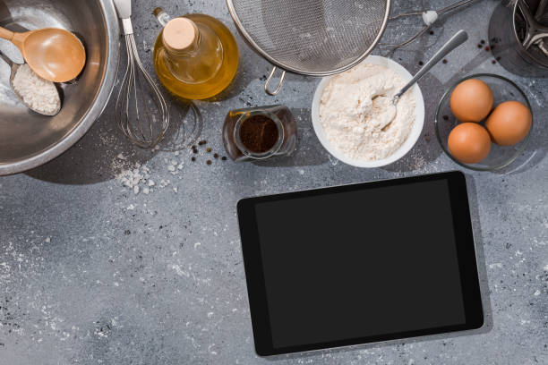 istock Ingredients, tools for baking and tablet with blank screen and place for text or image on gray table. recipe, cookbook, cooking courses online template 1303676118