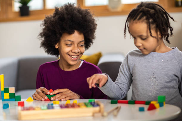 istock Cute sisters having fun playing with toy blocks at home 1303676517