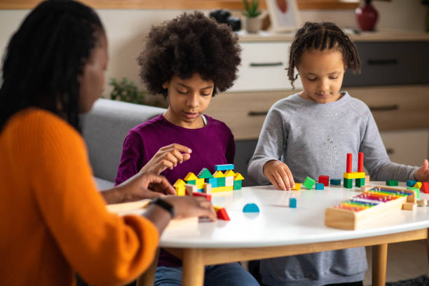 istock Mother and her two daughters playing together with toy blocks at home 1303676604