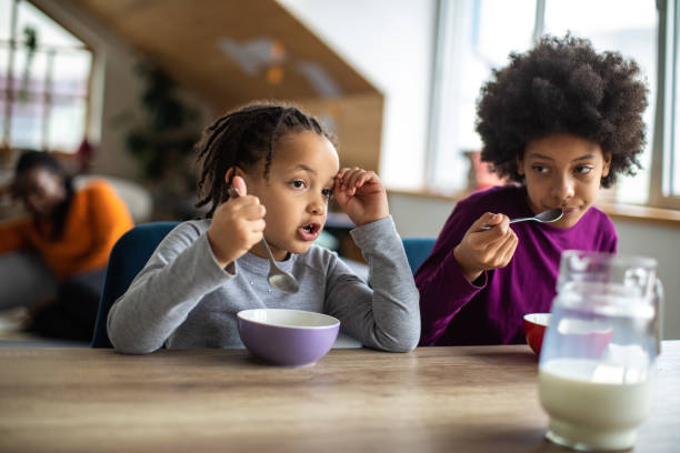 istock Two sisters eating cereals for breakfast in dining room 1303676654