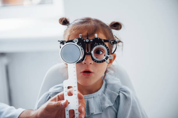 Little girl in eyewear in ophthalmology clinic have test of vision stock photo