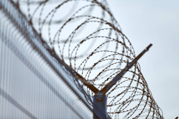 istock Barbed wire on fence of restricted area 1303678485