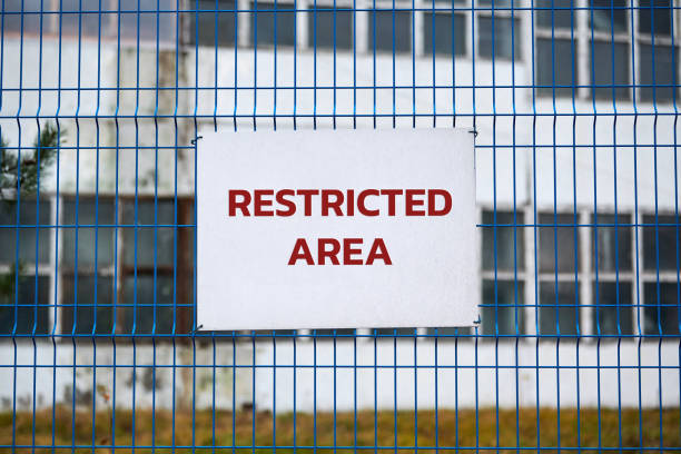 Restricted area, authorized personnel only â safety warning no trespassing sign. Red letters, keep off warning on metal fence, border symbol.