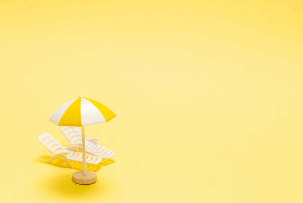 istock Two sun loungers and a red umbrella on a yellow background. 1303679294