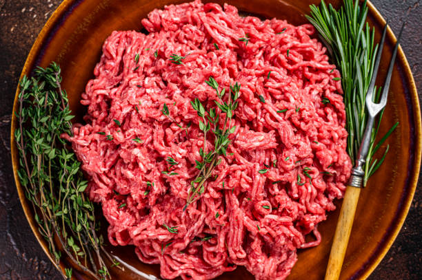 istock Raw ground beef or veal meat on a rustic plate with herbs. Dark background. Top view 1303679432