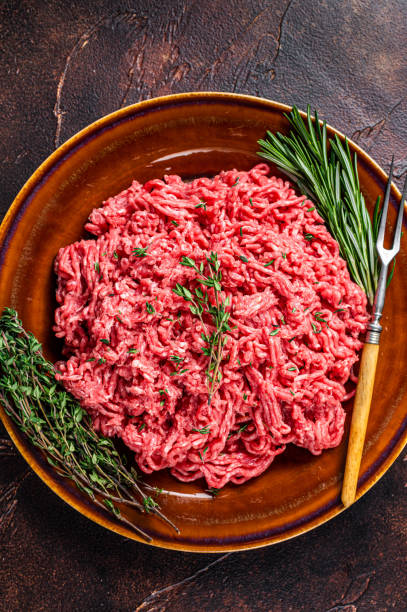 istock Raw ground beef or veal meat on a rustic plate with herbs. Dark background. Top view 1303679460